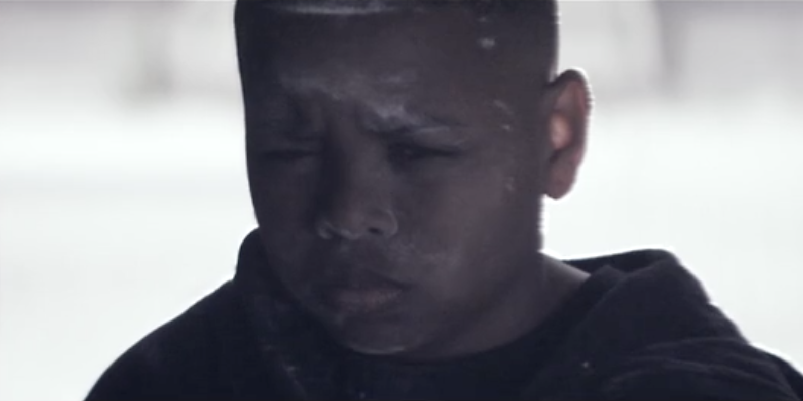 Boy Sitting Focussed In Stairwell With Flour Over His Face Wearing A Hoodie