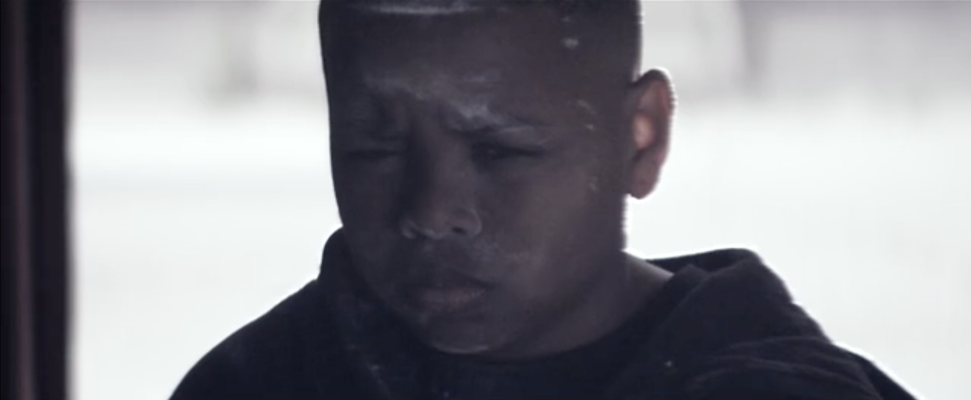 Boy Sitting Focussed In Stairwell With Flour Over His Face Wearing A Hoodie