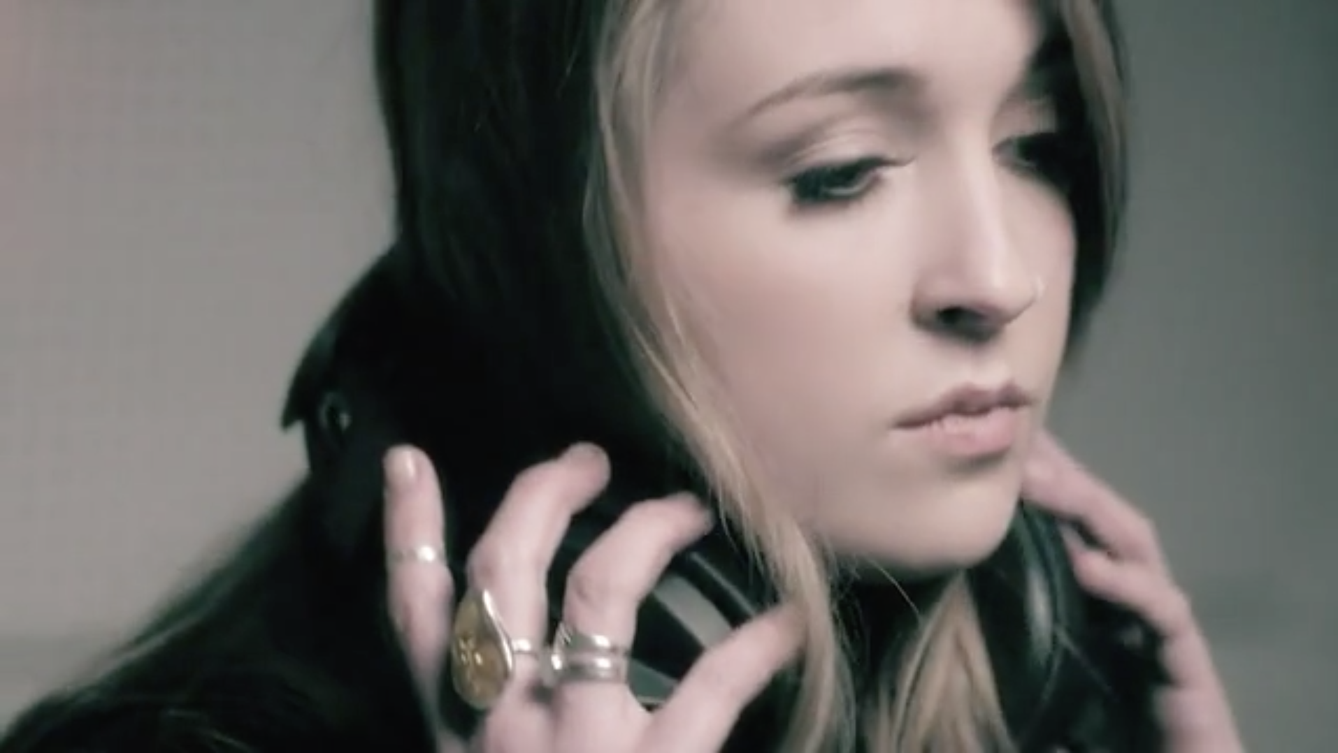 Singer Stands In Recording Booth Holding Headphones With Gemstone Rings