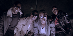 Cinematic music video production shot featuring a performance scene with a group of men on an urban London indoor football pitch.