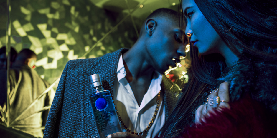 Male And Female Model Standing In London Club Stairwell Styled In High Fashion Man Holding Ciroc Vodka Bottle