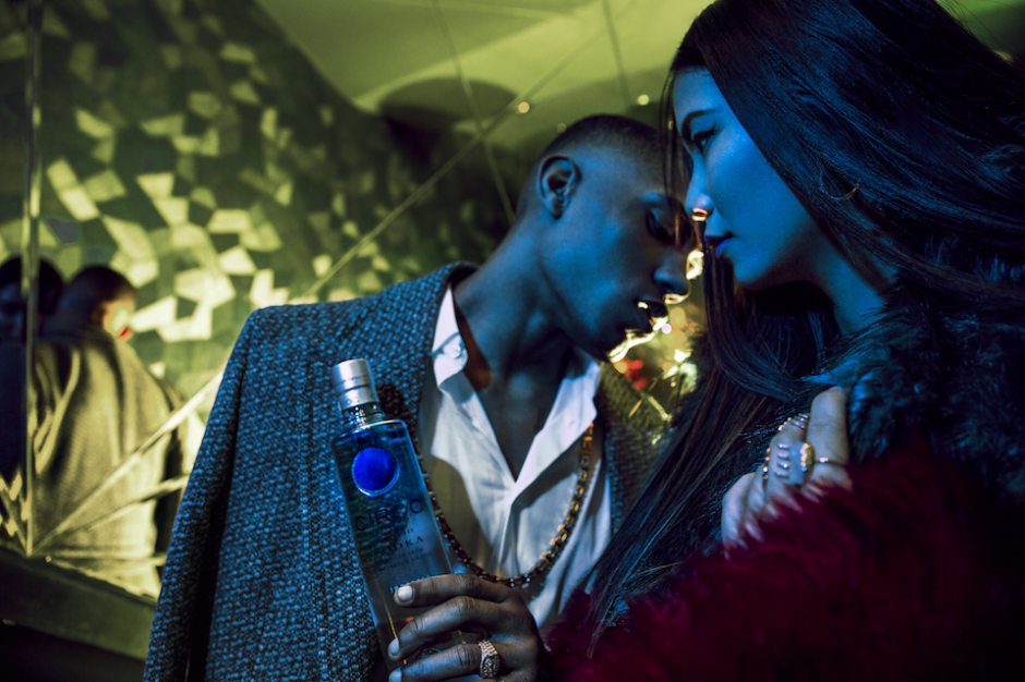 Male And Female Model Standing In London Club Stairwell Styled In High Fashion Man Holding Ciroc Vodka Bottle