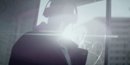 Cinematic brand film video production featuring a man at a bus stop wearing headphones with a bright lens flare background.