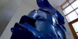Cinematic brand film production featuring an African-inspired blue sculpture in a university museum entrance.