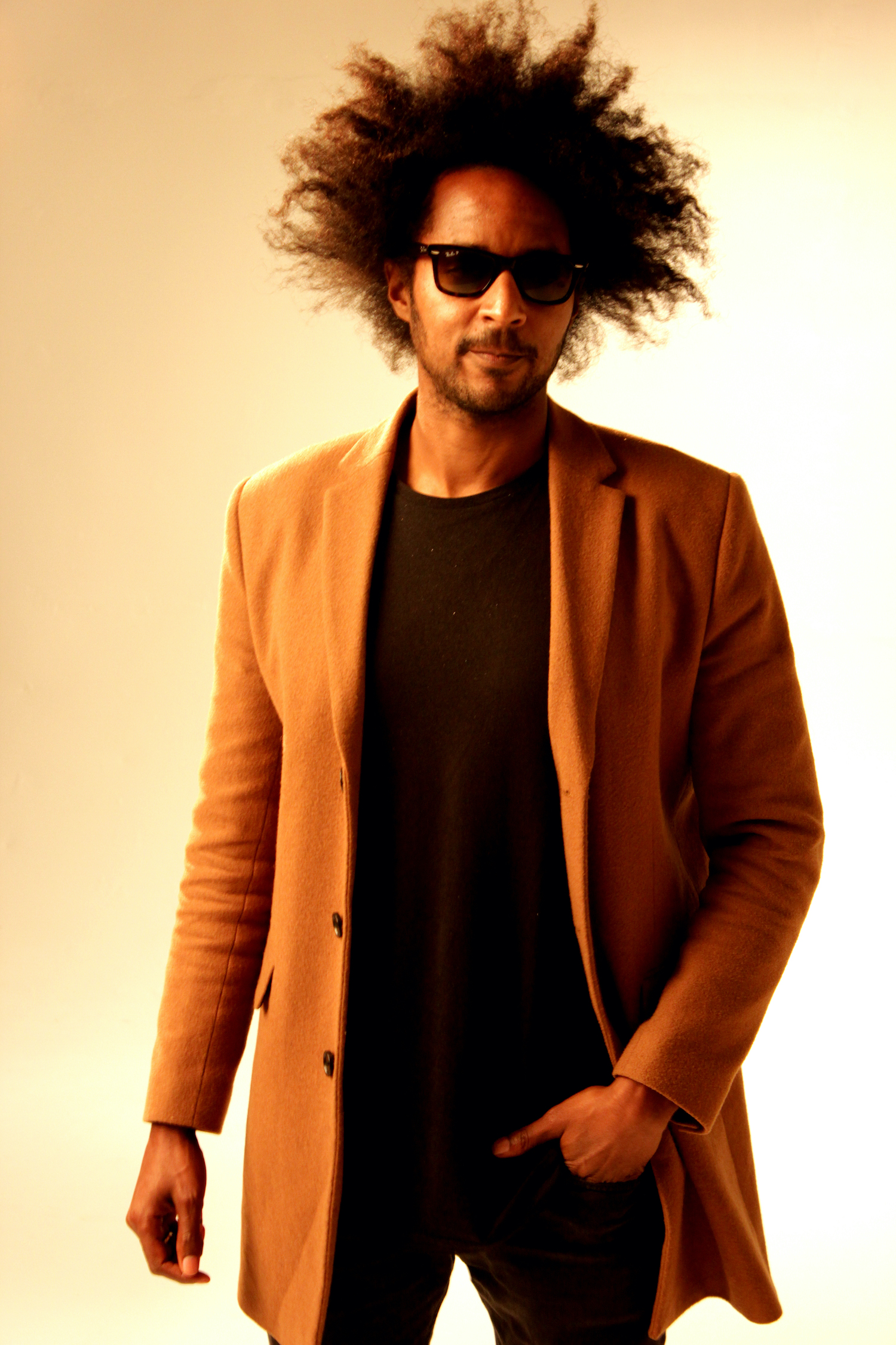 Professional Photography Black Man In Black Shirt Jeans Sunglasses And Orange Blazer Standing On White Studio Backdrop