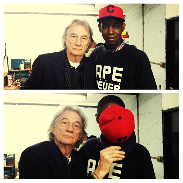 Professional Photography Black Man And White Man Standing In Bike Workshop One Holding Hat Over Face Of Other