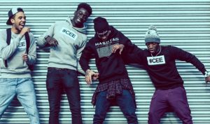 Professional Photography Four Black Men Wearing Hashtagcee And Generals Hoodies And Sweatshirts Pushing And Pulling In Front Of Grey Shutters