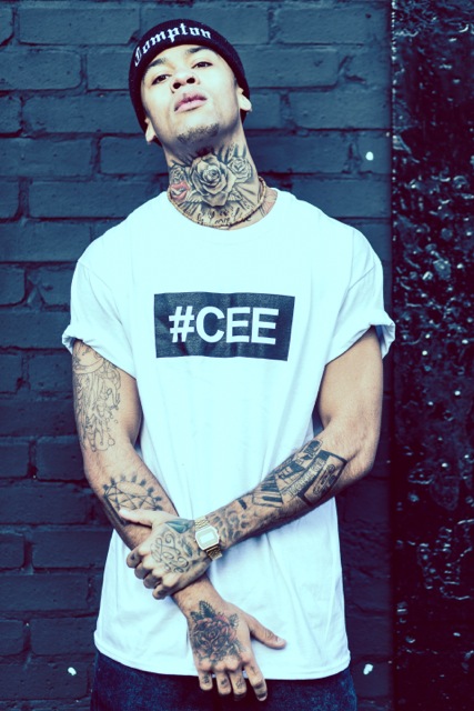 Professional Photography Black Man With Tattoos In Front Of Black Brick Wall Wearing White Hashtagcee Generals T-Shirt