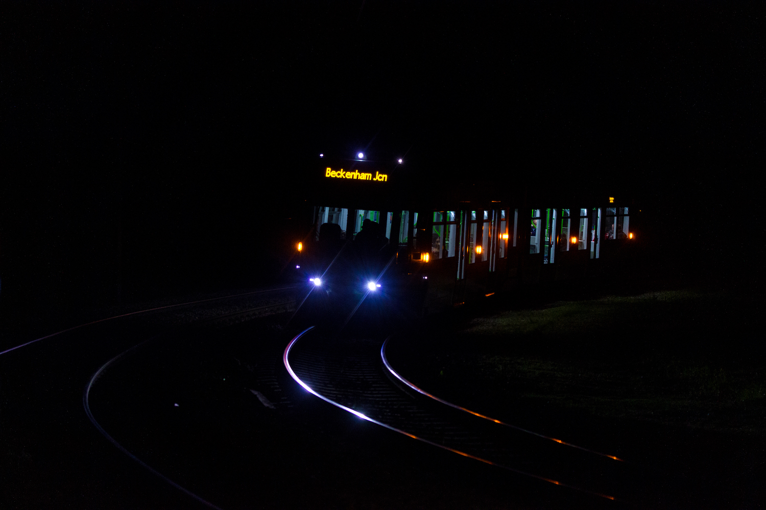 Professional Photography Tram Train At Night In Shadows With Bright Highlights Coming Around Bend In South Norwood London