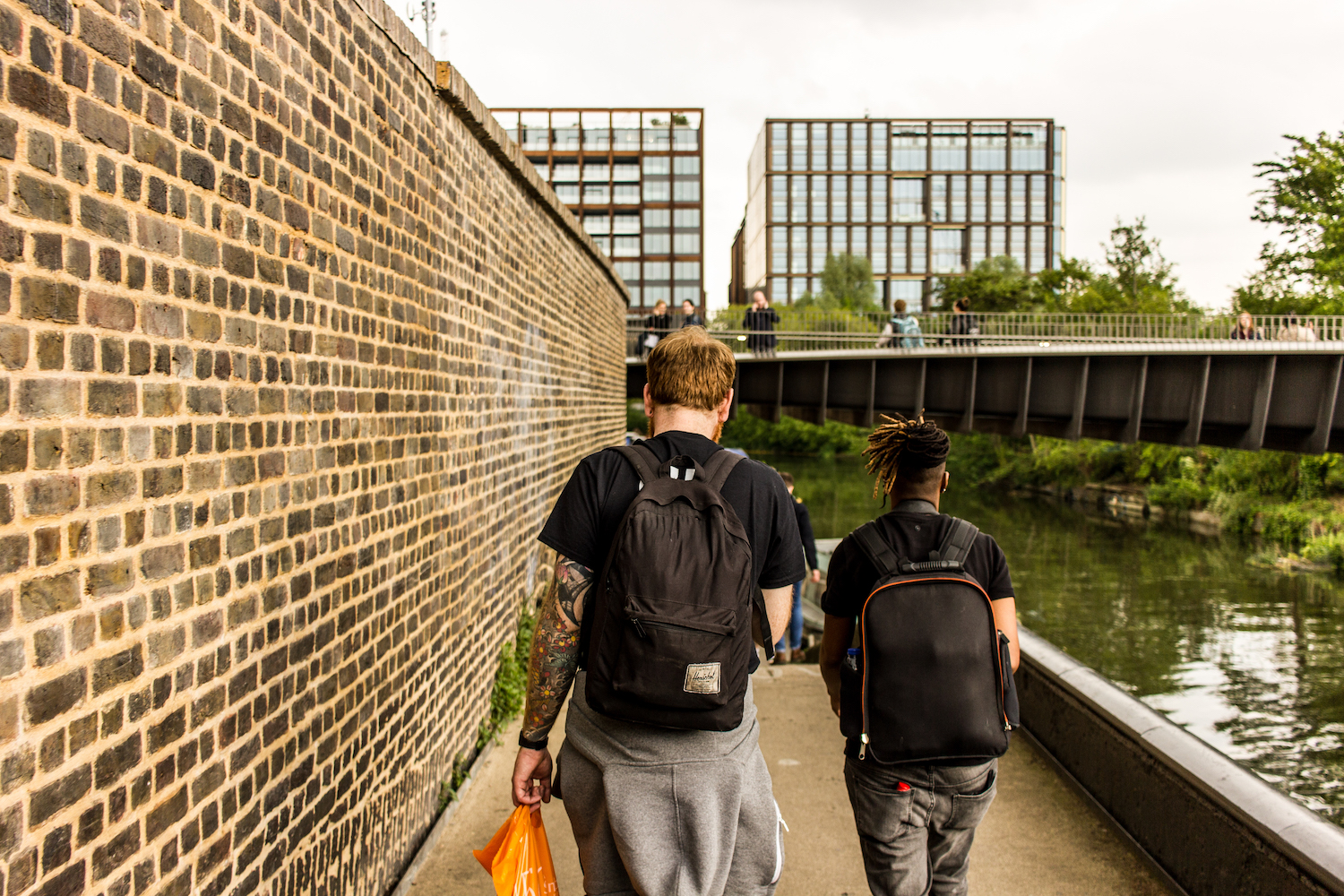 Professional Photography White Man With Beard Black T-Shirt And Black Backpack Walking With Dreadlocks Black Woman Wearing Black T-Shirt And Black Backpack Walking Alongside River Canal To Limehouse Basin