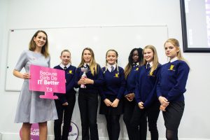 Professional Photography Six Female Students In Blue Sweatshirts Holding Silver And Pink Trophy At Event With Woman In Grey Dress